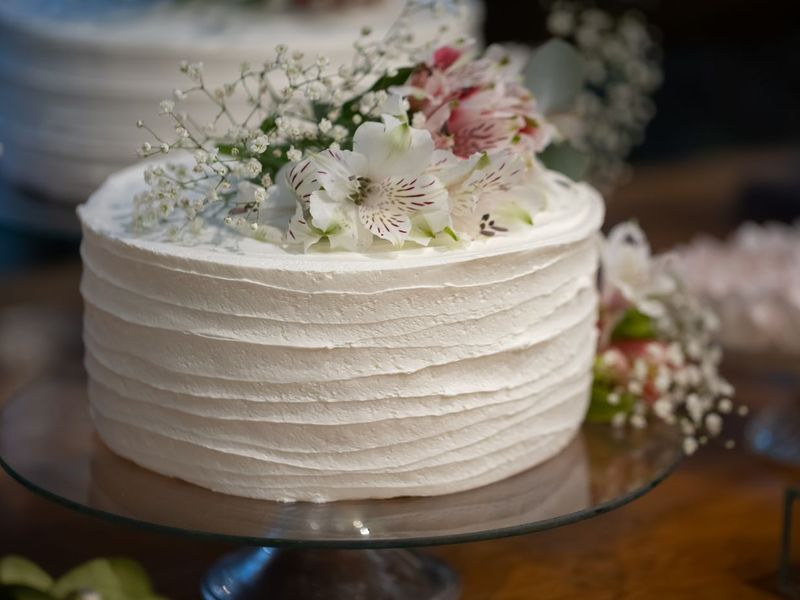 Elegante weisse Buttercremetorte mit feinen Linien und zarten Blüten