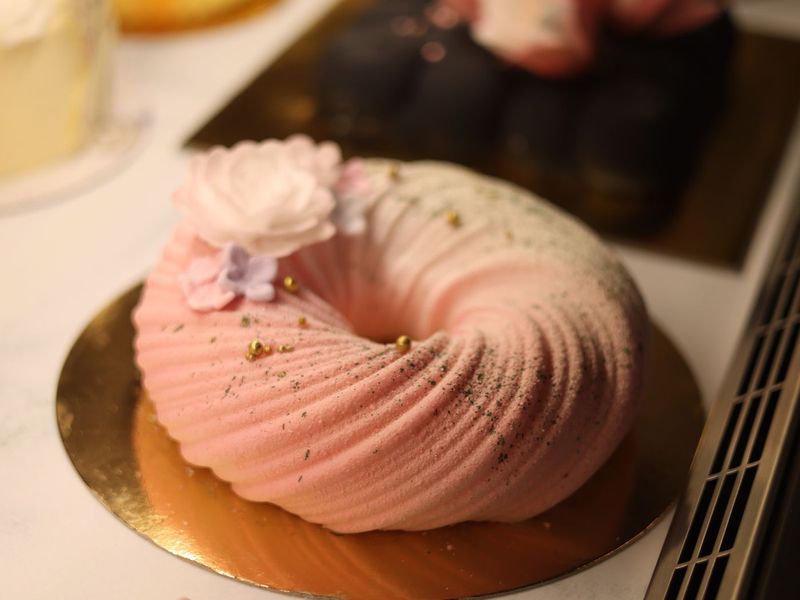 Skulpturale ringförmige Torte in Rosa mit Zuckerblüten und Goldperlen