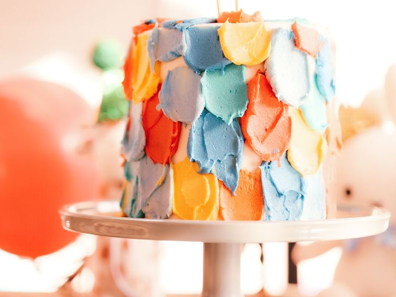 Bunte Torte mit farbigen Buttercreme-Tupfen auf einer hellen Etagere